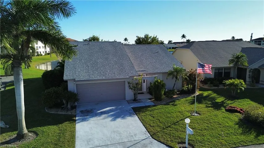 View of front facade featuring driveway, roof with shingles, a front yard, a garage, and stucco siding