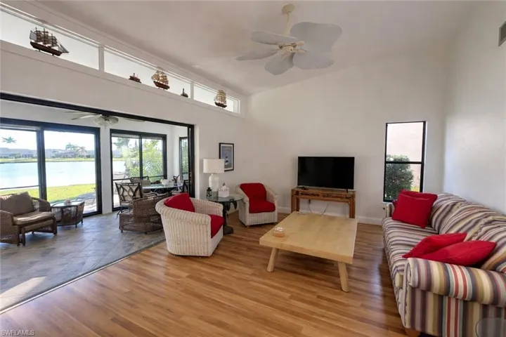 Living room featuring wood finished floors, ceiling fan, high vaulted ceiling, and a water view