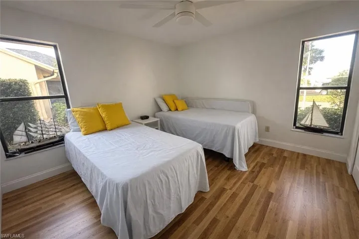 Bedroom with light wood finished floors, multiple windows, and a ceiling fan