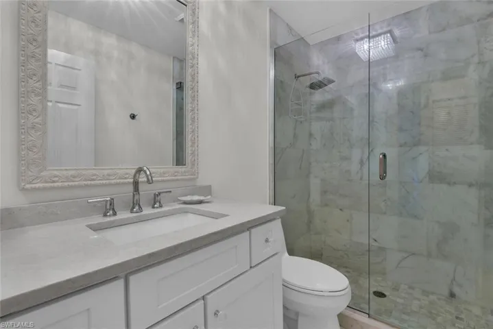 Bathroom with a marble finish shower and vanity