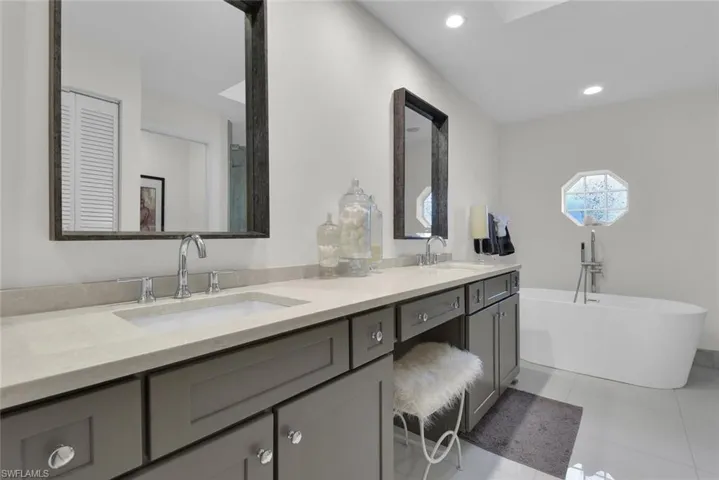 Full bathroom featuring double vanity, a freestanding tub, tile patterned floors, and recessed lighting