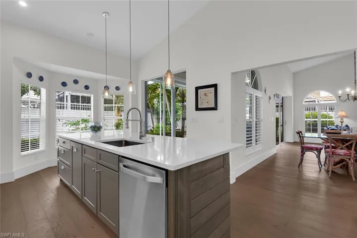 Kitchen featuring stainless steel dishwasher, gray cabinetry, light countertops, dark wood-style floors, and a chandelier