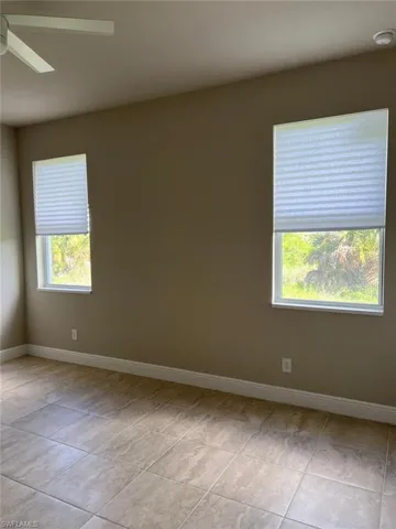 Spare room with ceiling fan and light tile patterned floors