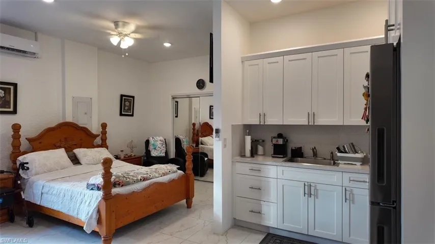 Bedroom with freestanding refrigerator, light marble finish flooring, electric panel, a ceiling fan, and recessed lighting