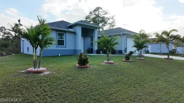 Ranch-style house with stucco siding, a front lawn, and driveway