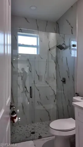 Bathroom with vanity and a marble finish shower