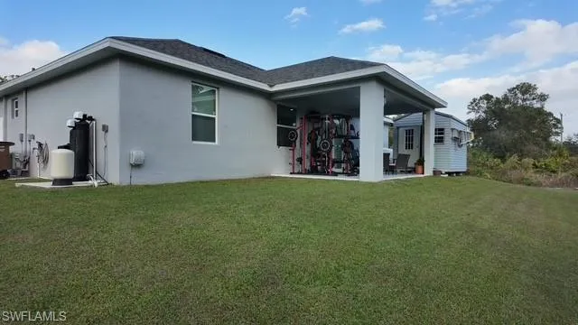 Rear view of house with a patio area, a lawn, and stucco siding