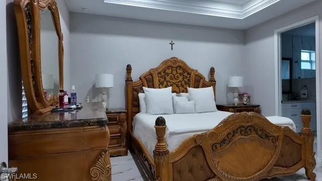 Bedroom featuring crown molding, ensuite bathroom, and a tray ceiling