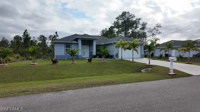 Ranch-style home featuring driveway, a front lawn, stucco siding, and a garage