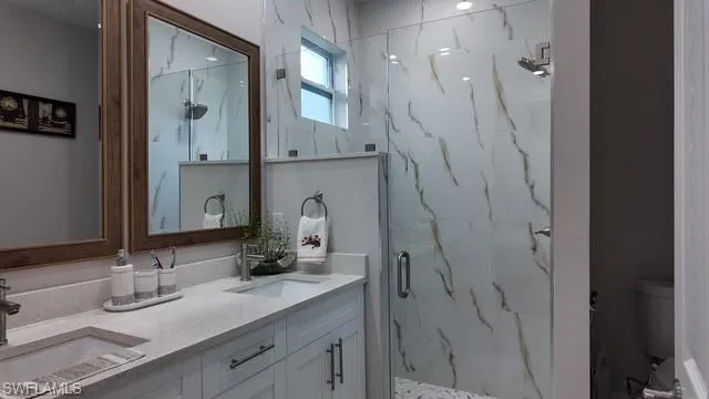 Bathroom with double vanity and a marble finish shower