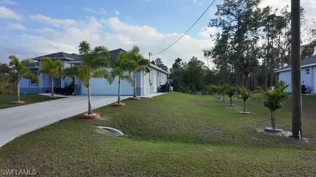 View of front of property with concrete driveway, a front yard, and a garage