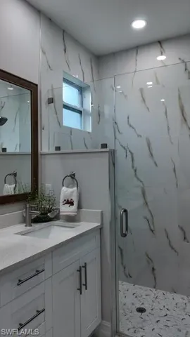 Full bathroom with vanity and a marble finish shower