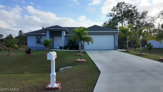 Ranch-style house featuring concrete driveway, a front lawn, stucco siding, and a garage