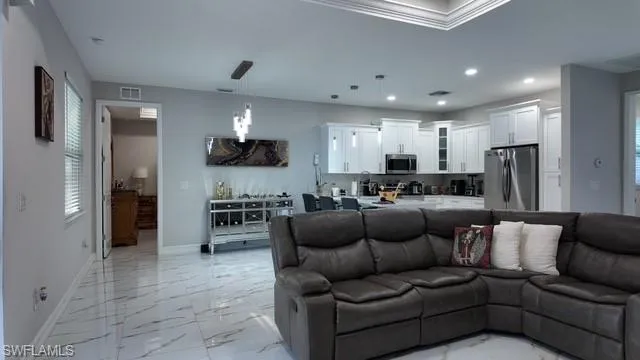 Living room with plenty of natural light, light marble finish floors, recessed lighting, and ornamental molding