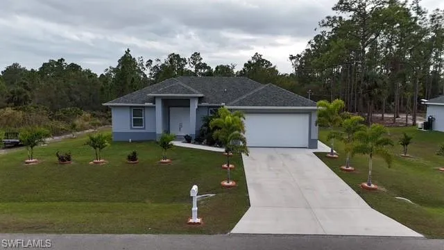 Ranch-style house featuring driveway, a front lawn, and stucco siding