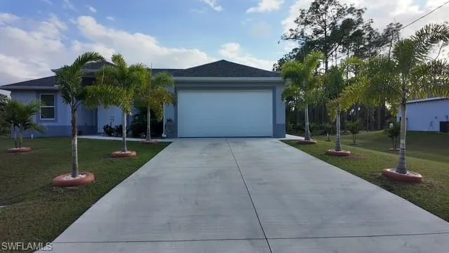 View of front of property featuring a front yard, concrete driveway, a garage, and stucco siding
