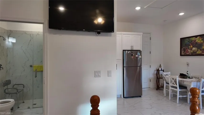 Kitchen featuring light marble finish flooring, freestanding refrigerator, white cabinetry, and recessed lighting