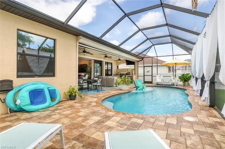 View of swimming pool featuring a lanai, ceiling fan, and a patio