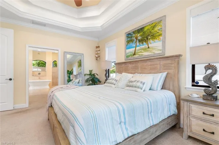 Bedroom with light colored carpet, ceiling fan, ornamental molding, and ensuite bathroom