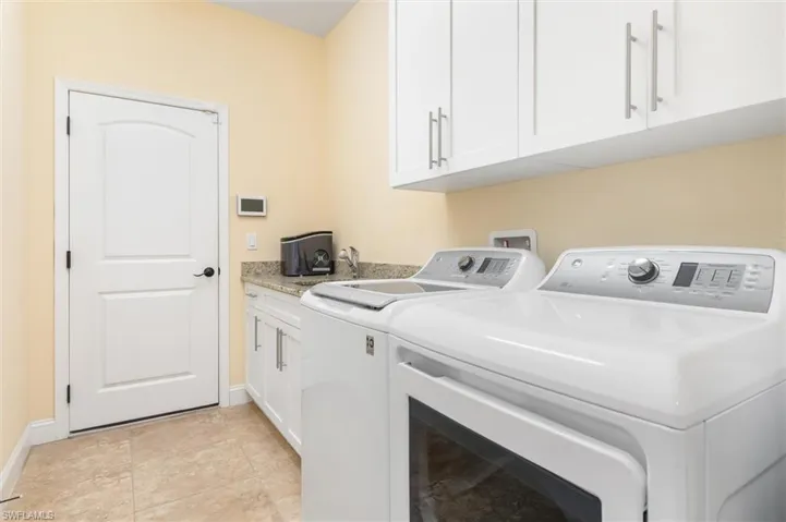 Laundry room featuring cabinets, washer and clothes dryer, and light tile patterned flooring