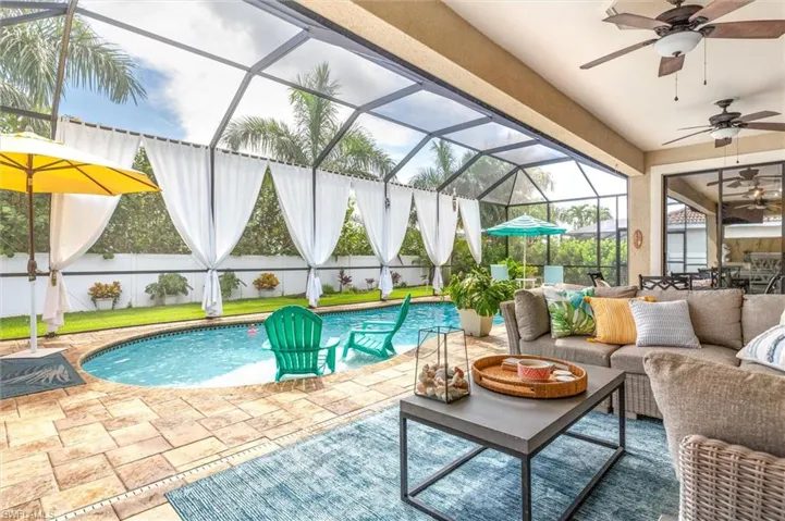View of pool featuring outdoor lounge area, ceiling fan, a patio area, and glass enclosure