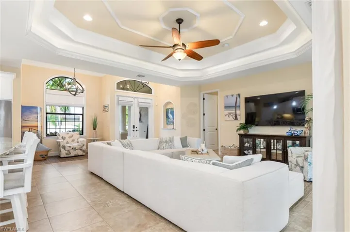 Living room featuring crown molding, ceiling fan, a raised ceiling, and french doors