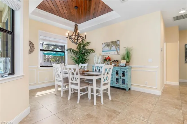 Dining room with a tray ceiling, an inviting chandelier, crown molding, and wooden ceiling