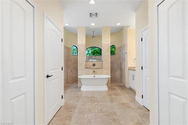Bathroom featuring tile walls, shower with separate bathtub, and vanity