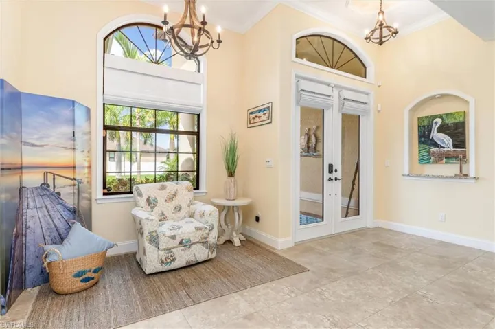 Foyer entrance featuring ornamental molding, french doors, a towering ceiling, and a chandelier