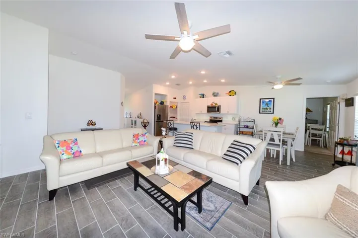 Living room with wood tiled floors, a ceiling fan, and recessed lighting