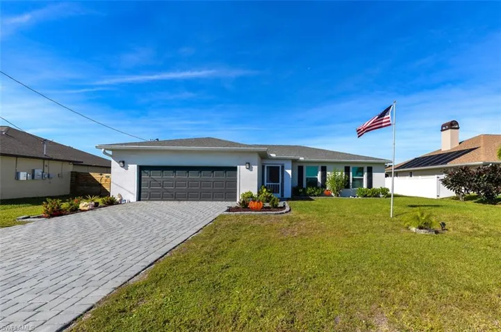 View of front facade with stucco siding, decorative driveway, and an attached garage