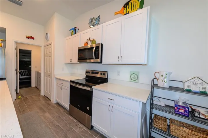 Kitchen featuring stainless steel appliances, white cabinets, wood finish floors, and light stone counters