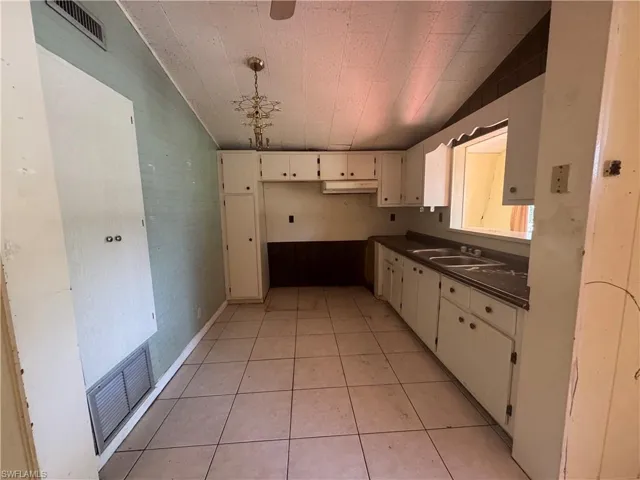 Kitchen featuring under cabinet range hood, dark countertops, light tile patterned flooring, and cream cabinetry