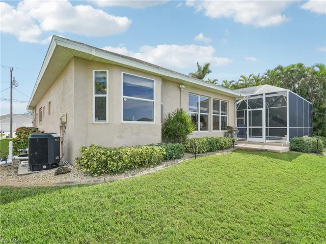 Rear view of property featuring a yard, central AC, and glass enclosure