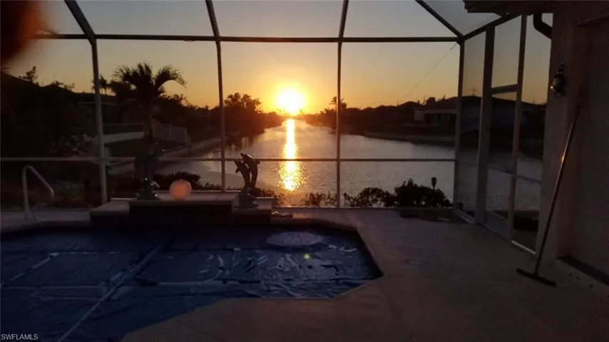 Pool at dusk with a lanai and a water view