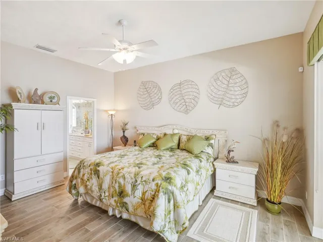 Bedroom with ceiling fan, light hardwood / wood-style floors, and connected bathroom