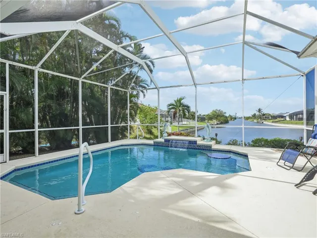 View of pool with a lanai, a water view, a patio, and pool water feature