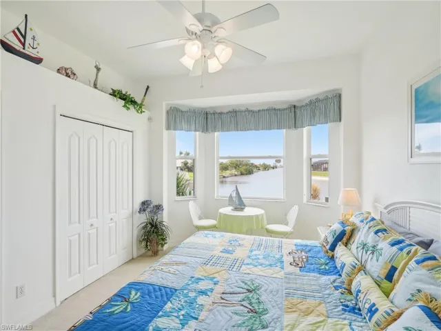 Carpeted bedroom with ceiling fan and a closet