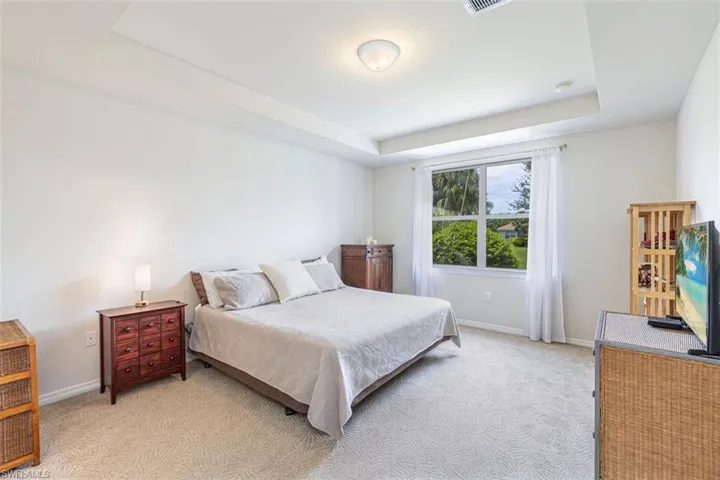 Bedroom with a tray ceiling and light carpet