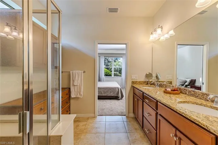 Bathroom featuring ensuite bathroom, double vanity, light tile patterned floors, and a shower stall