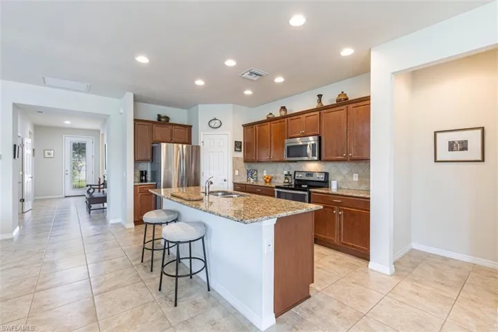 Kitchen with a breakfast bar area, backsplash, light Granite countertops, recessed lighting, and stainless steel appliances