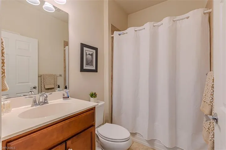 Bathroom with shower / tub combo, vanity, and light tile patterned floors