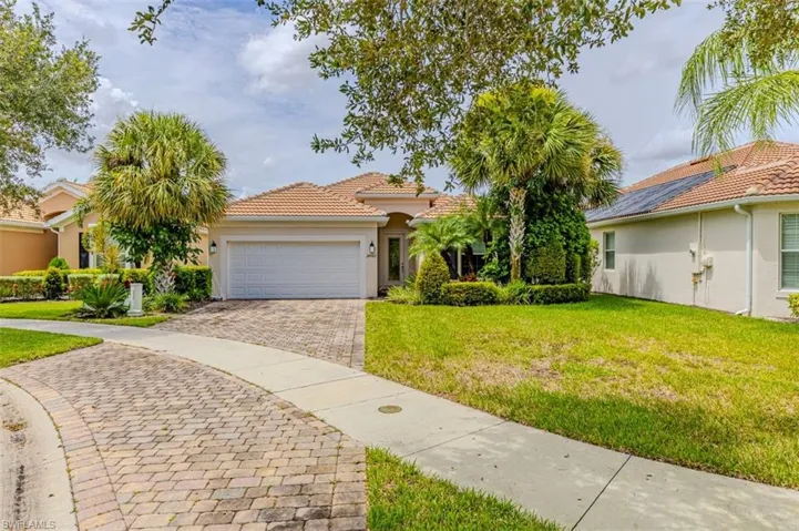 Mediterranean / spanish home with a front lawn, stucco siding, decorative driveway, a garage, and a tiled roof