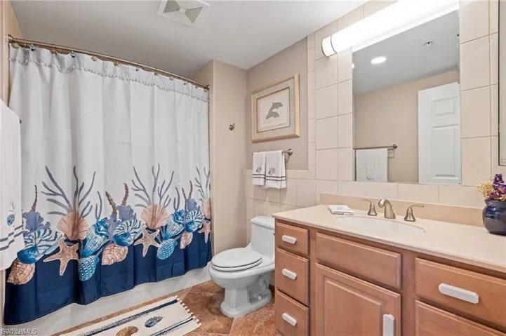 Full bath with tile walls, vanity, a shower with curtain, light tile patterned flooring, and tasteful backsplash