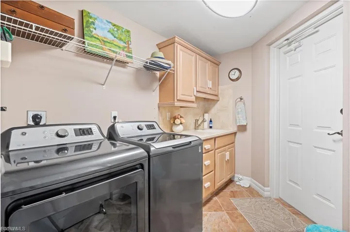 Laundry room with light tile patterned flooring, washer and dryer, and cabinet space