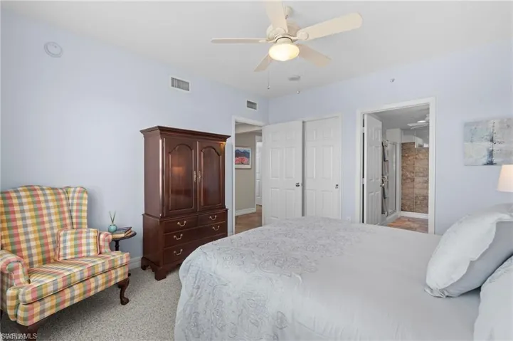 Bedroom featuring ensuite bathroom, light colored carpet, and ceiling fan