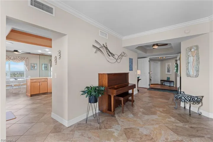 Hallway with ornamental molding and a tray ceiling