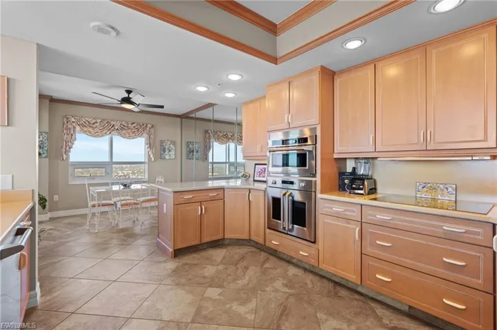 Kitchen with crown molding, recessed lighting, a peninsula, a ceiling fan, and appliances with stainless steel finishes