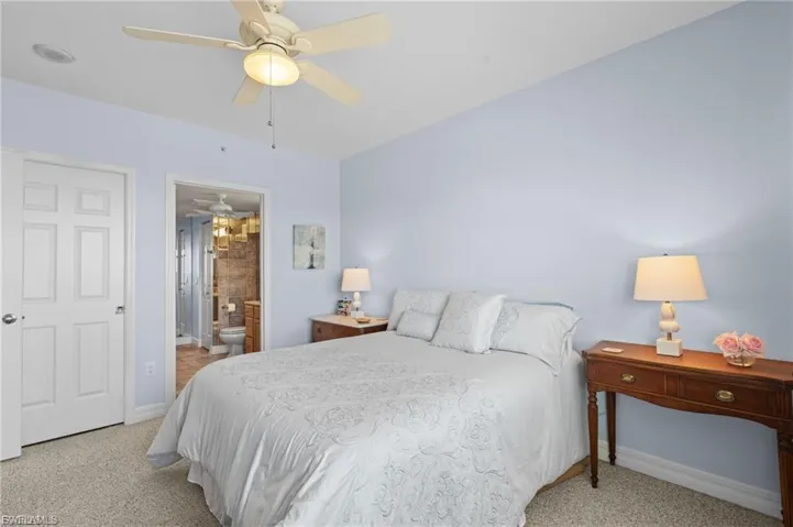 Bedroom featuring light carpet, ensuite bathroom, and a ceiling fan