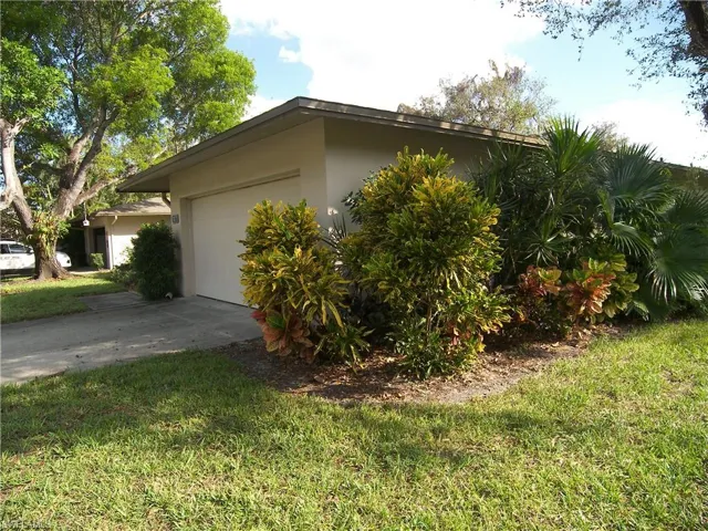 View of side of home featuring a lawn and a garage
